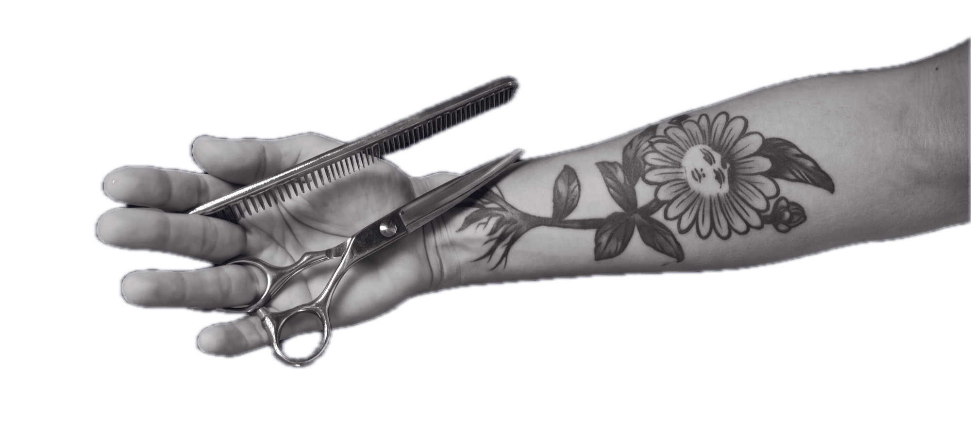 Mano tatuada sosteniendo tijeras y peine